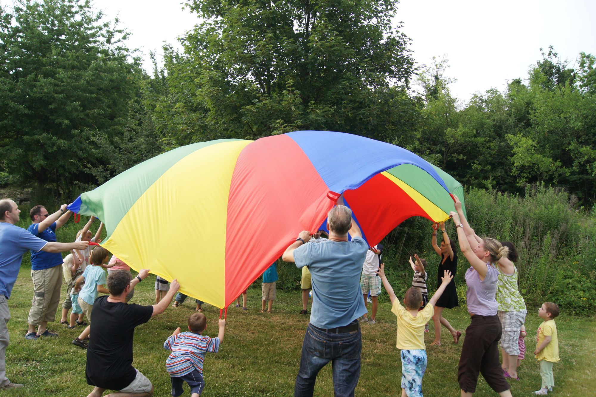Familien, die buntes Segeltuch spannen