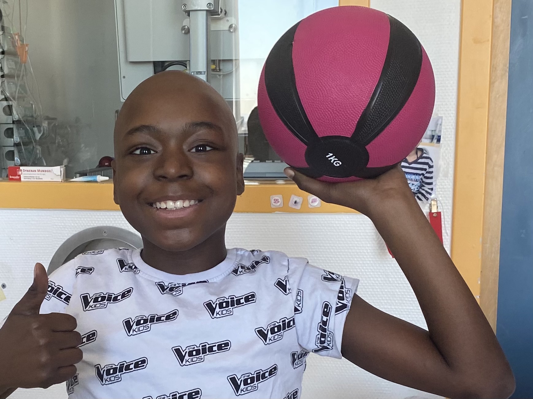 krebskrankes kind mit basketball, das den daumen nach oben streckt