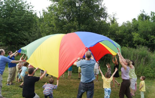 Familien, die gemeinsam ein buntes Segeltuch spannen